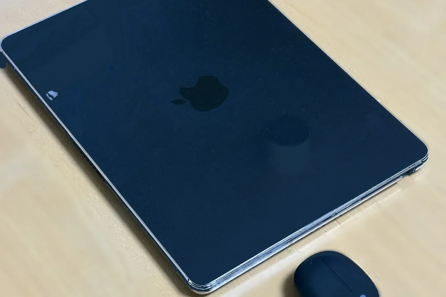 MacBook Airの天板のリンゴマークとShokzのイヤホンケースを写した実物写真