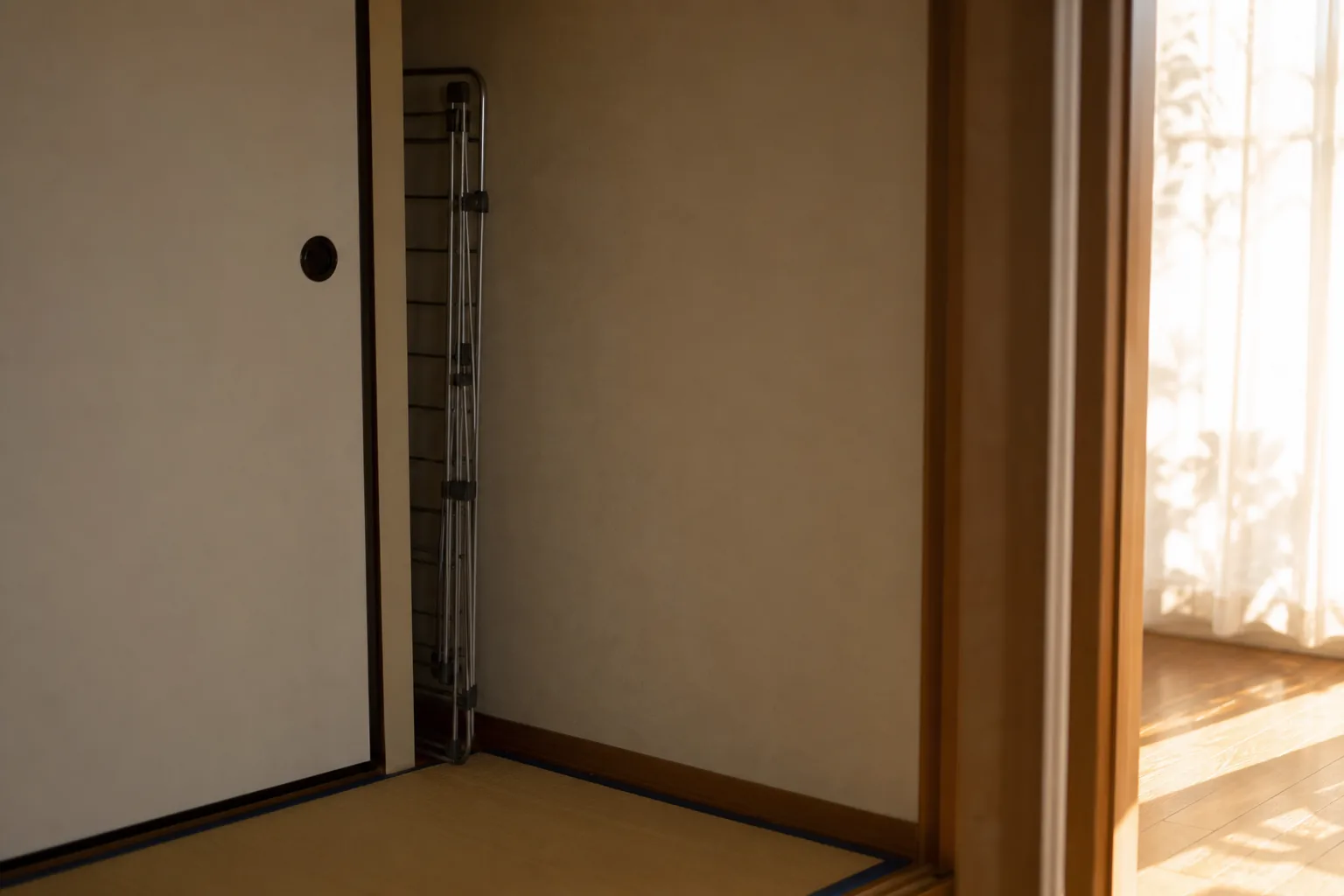 部屋の隅に畳まれて仕舞われた物干しスタンドと夕方の光
