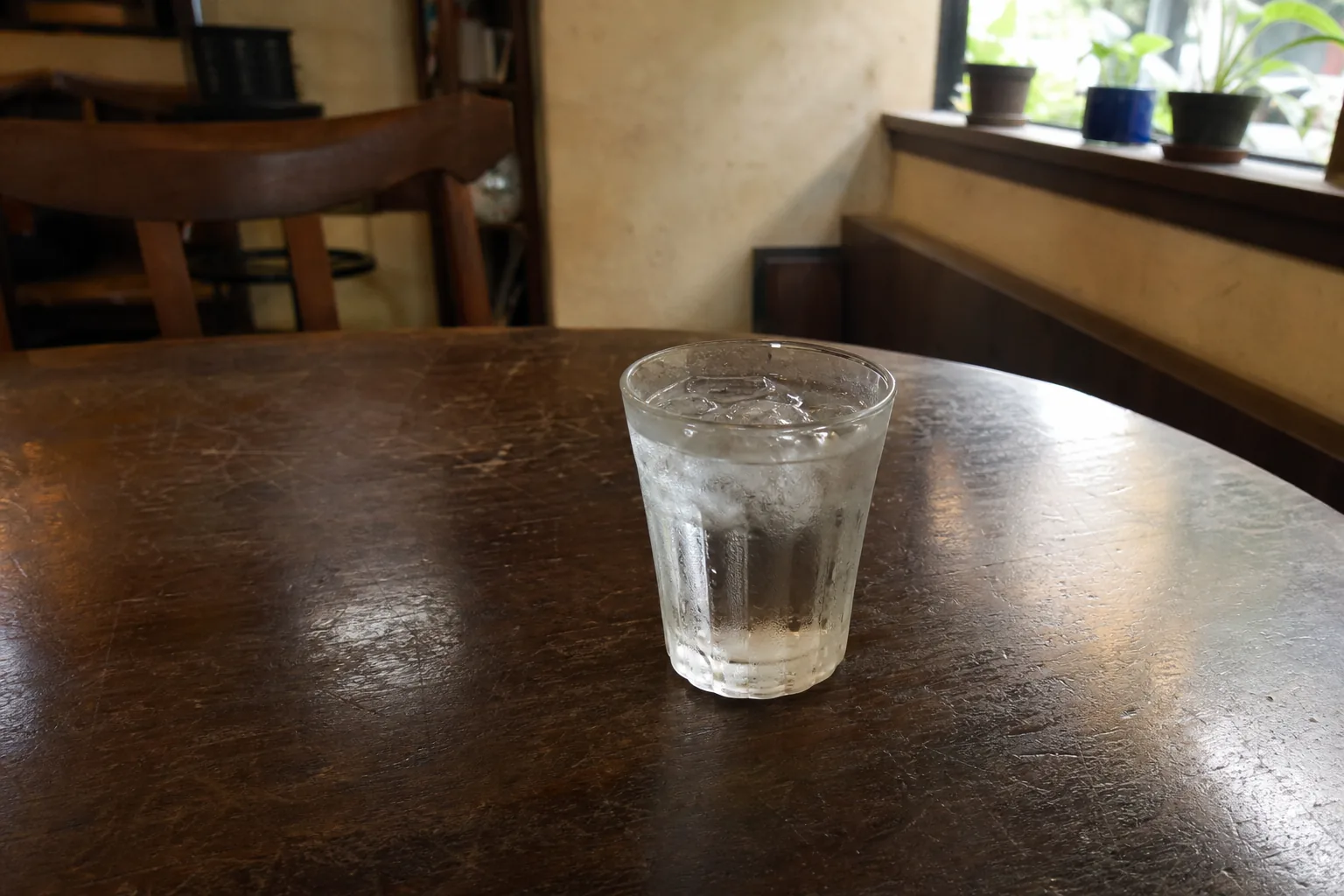 夏の喫茶店のテーブルに置かれた水滴のついたグラス